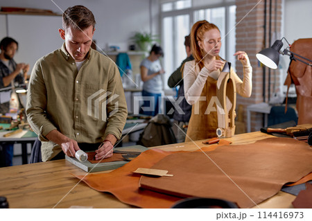 handsome guy punctures holes in leather handsome guy punctures holes in leather 114416973