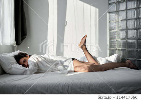 Sexy man lying on silk white bed. Sexy man lying on silk white bed. 114417060