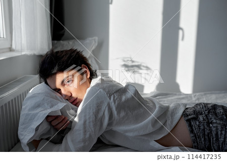 unhappy depressed serious man hugging pillow in bedroom 114417235