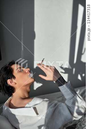 handsome man smoking cannabis weed at home and using his lighter handsome man smoking cannabis weed at home and using his lighter 114417318