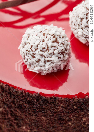 Coconut truffles on red glaze decorating handmade chocolate cake 114418264