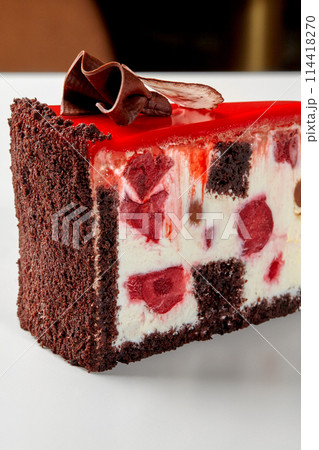 Slice of chocolate cake with sour cream, berries and red icing Slice of chocolate cake with sour cream, berries and red icing 114418270
