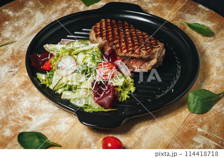 Grilled Steak Served With Fresh Garden Salad on a Black Plate 114418718