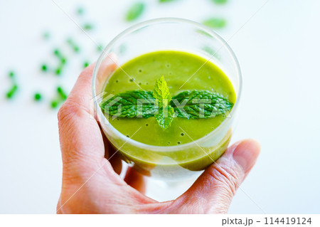 オーガニック野菜と果物で作ったグリーンスムージーのグラスを持つ女性の手元 オーガニック野菜と果物で作ったグリーンスムージーのグラスを持つ女性の手元 114419124