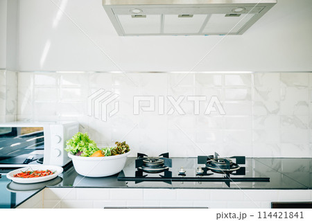 Kitchen space in a luxurious house gas stove by a bright window. Modern design clean furniture steel appliances. Comfortable cooking setup empty dining table perfect for modern living give me. 114421841