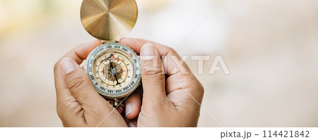 Surrounded by the beauty of nature a woman's hand grips a compass in a tranquil forest and lake setting. The image symbolizes guidance and the exciting spirit of exploration amidst the outdoors. Surrounded by the beauty of nature a woman's hand grips a compass in a tranquil forest and lake setting. The image symbolizes guidance and the exciting spirit of exploration amidst the outdoors. 114421842
