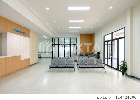 Waiting area in a hospital. Patient or visitor can check in for appointment or service. There are rows of connected grey seating for individual waiting. Glass door on the right lead to emergency area. Waiting area in a hospital. Patient or visitor can check in for appointment or service. There are rows of connected grey seating for individual waiting. Glass door on the right lead to emergency area. 114424200
