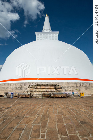 View of Ruwanwelisaya stupa in ancient city of Anuradhapura, Sri Lanka. Ruwanwelisaya stupa is one of the world's tallest ancient monuments and containing Buddha relics. View of Ruwanwelisaya stupa in ancient city of Anuradhapura, Sri Lanka. Ruwanwelisaya stupa is one of the world's tallest ancient monuments and containing Buddha relics. 114424784