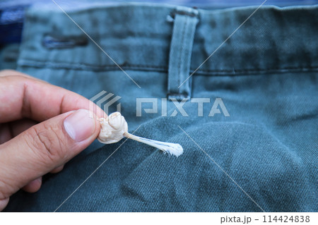 hand pulling gum stick on pants from accident in daily life. dirty stain for cleaning concept. 114424838