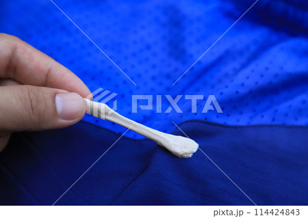 hand pulling gum stick on pants from accident in daily life. dirty stain for cleaning concept. hand pulling gum stick on pants from accident in daily life. dirty stain for cleaning concept. 114424843