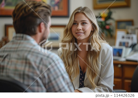 A young psychiatrist with long blonde hair and a gentle expression engages in a warm dialogue with a patient, providing a comforting and open environment. 114426326