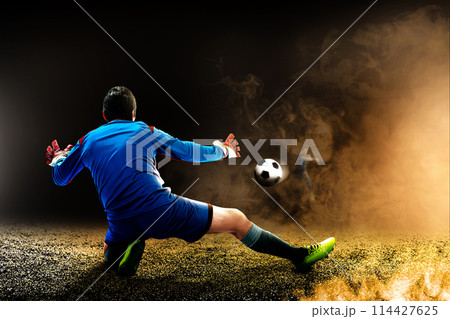 Portrait of a male goalkeeper trying to stop the ball on the pitch 114427625