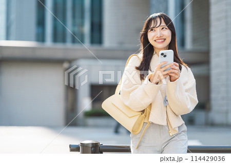 街中でスマホを使う若い女性 114429036