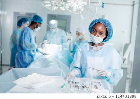 good looking american doctor holding forceps and posing to the camera 114431899