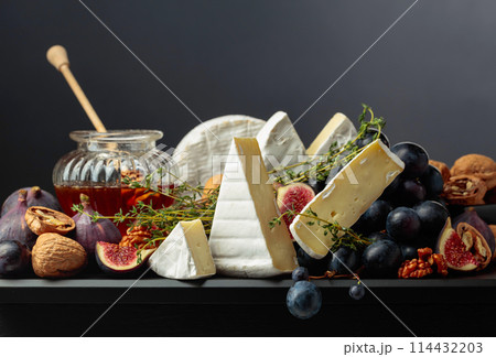 Camembert cheese with fruits and honey on a black background. Camembert cheese with fruits and honey on a black background. 114432203