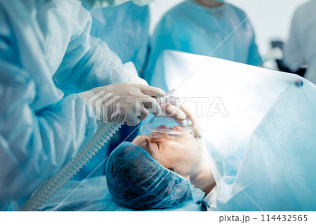 doctor in gloves holding the oxygen mask firmly against patient's face. 114432565
