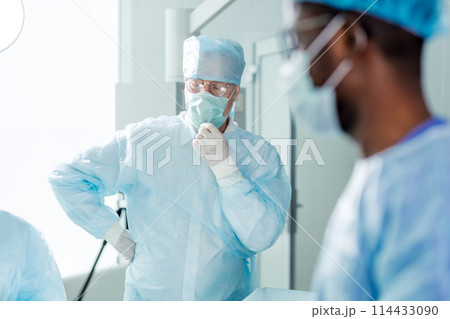 tired physician with close eyes touching surgical mask tired physician with close eyes touching surgical mask 114433090