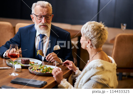 Pretty lady and elderly man having friendly conversation in restaurant Pretty lady and elderly man having friendly conversation in restaurant 114433325