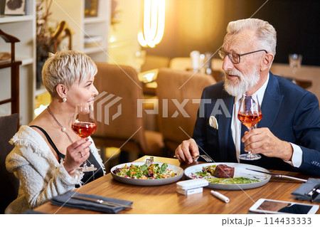 Stylish senior couple taking meal in restaurant, using electronic cigarette. IQOS Stylish senior couple taking meal in restaurant, using electronic cigarette. IQOS 114433333
