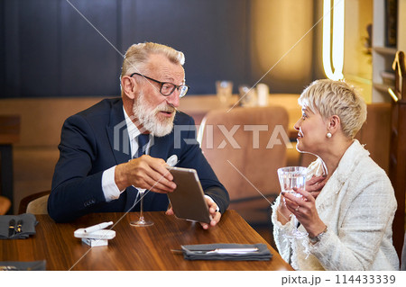 Beautuful senior couple with digital tablet in restaurant Beautuful senior couple with digital tablet in restaurant 114433339
