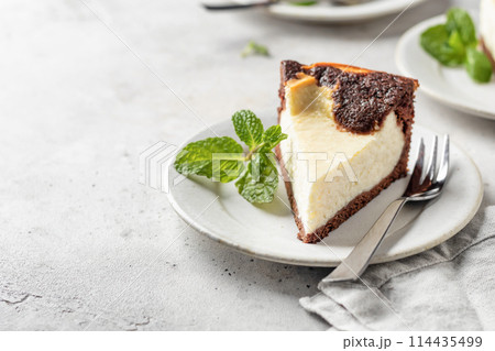 Piece of homemade chocolate cheesecake with mint leave on a plate on white textured background with copy space Piece of homemade chocolate cheesecake with mint leave on a plate on white textured background with copy space 114435499