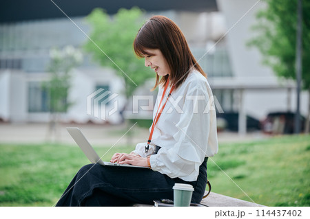 公園でパソコンを操作する若い女性 公園でパソコンを操作する若い女性 114437402