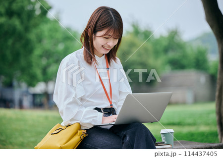 公園でパソコンを操作する若い女性 114437405