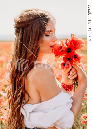 Woman poppies field. Side view of a happy woman with long hair in a poppy field and enjoying the beauty of nature in a warm summer day. 114437796