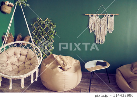 A cozy relaxation room, a living room interior with a designer upholstered armchair and a boho style chair. A cozy living room. Home decor with copy space. High quality photo A cozy relaxation room, a living room interior with a designer upholstered armchair and a boho style chair. A cozy living room. Home decor with copy space. High quality photo 114438996
