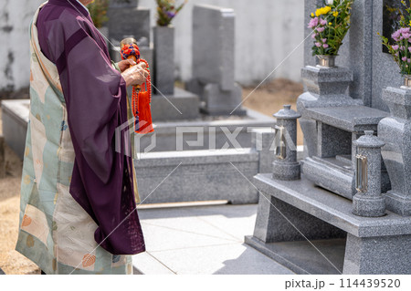 永代供養墓の前で読経するお坊さん 114439520
