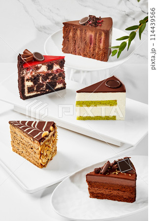 Slices of various cakes arranged on plates on marble surface 114439566