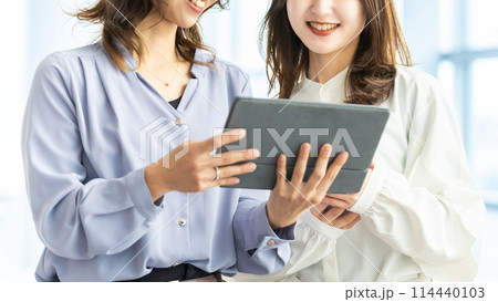 タブレットを見ながら話す2人のビジネスウーマン 114440103