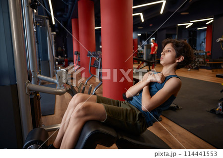 Weak skinny preteen boy pumping up his abs doing fitness exercise Weak skinny preteen boy pumping up his abs doing fitness exercise 114441553