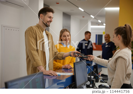 Young couple paying for doctor appointment at clinic reception using smartphone Young couple paying for doctor appointment at clinic reception using smartphone 114441756
