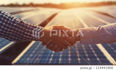 Firm representatives engage in a handshake before an expanse of solar panels, signifying alliances fostered for green initiatives. Corporate carbon reduction 114441900