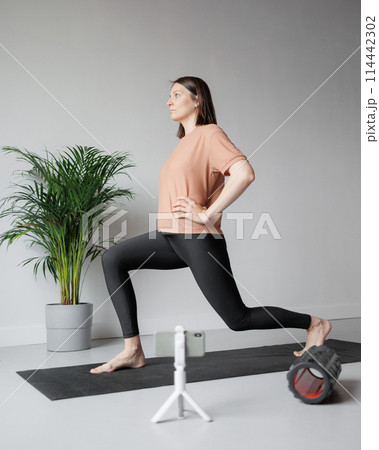 young Caucasian woman does sports online, stretches, practices yoga, meditation in gym 114442302