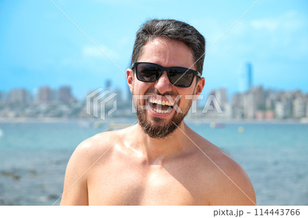 Young Hispanic man model smiling with sunglasses on beach looking to camera 114443766
