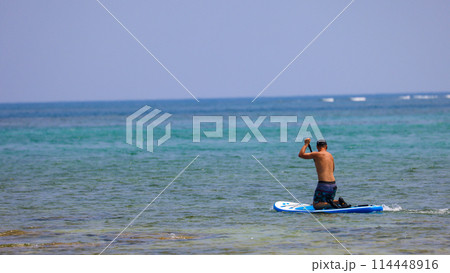 沖縄県の綺麗に海でサップを楽しむ男性 114448916