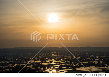 水が張られた田んぼに美しく反射する太陽の夕景｜散居村展望広場より撮影｜富山県砺波市 114449031