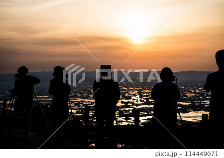 水が張られた田んぼに美しく反射する太陽の夕景を散居村展望広場で撮影する人のシルエット|富山県砺波市 水が張られた田んぼに美しく反射する太陽の夕景を散居村展望広場で撮影する人のシルエット|富山県砺波市 114449071