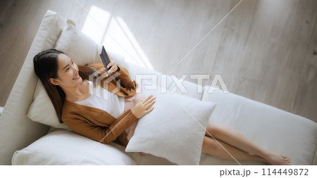High angle view of happy cheerful positive young Asian woman on the phone at home High angle view of happy cheerful positive young Asian woman on the phone at home 114449872
