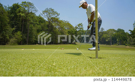 Golfer putting ball on the green golf, lens flare on sun set evening time. Golfer putting ball on the green golf, lens flare on sun set evening time. 114449878