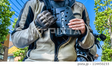 バイク用胸部プロテクターを準備する男性ライダー 114450233
