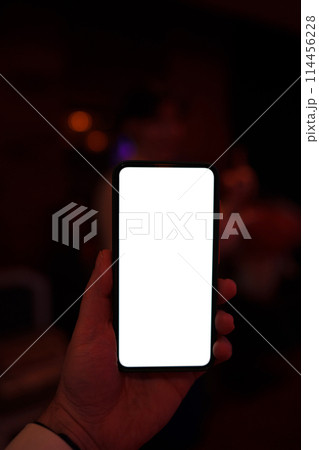 Person holding a portable communications device with a white display screen 114456228