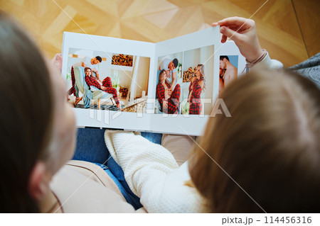 mother and daughter flips through a book with photos of dad and pregnant mom. mother and daughter flips through a book with photos of dad and pregnant mom. 114456316
