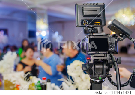 A professional camera on the blurred background of a banquet hall.  114456471
