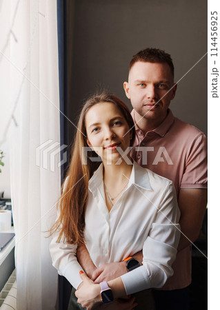 Happy married couple hugging at the window in the apartment. Happy married couple hugging at the window in the apartment. 114456925