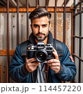 A dark-skinned male photographer with a beard in prison.  114457220