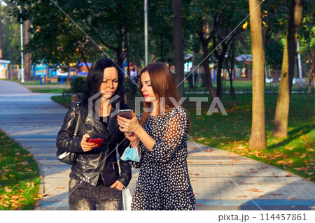 Two girlfriends, young women discussing the news, looking at the phone Two girlfriends, young women discussing the news, looking at the phone 114457861