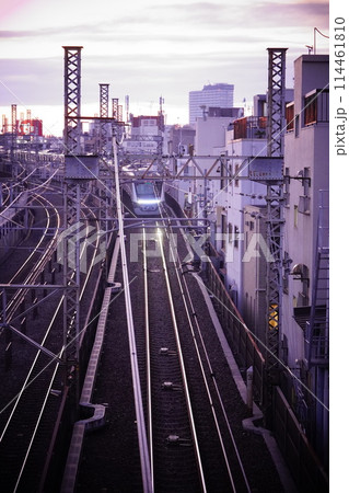 夕暮れの線路を走る電車 114461810